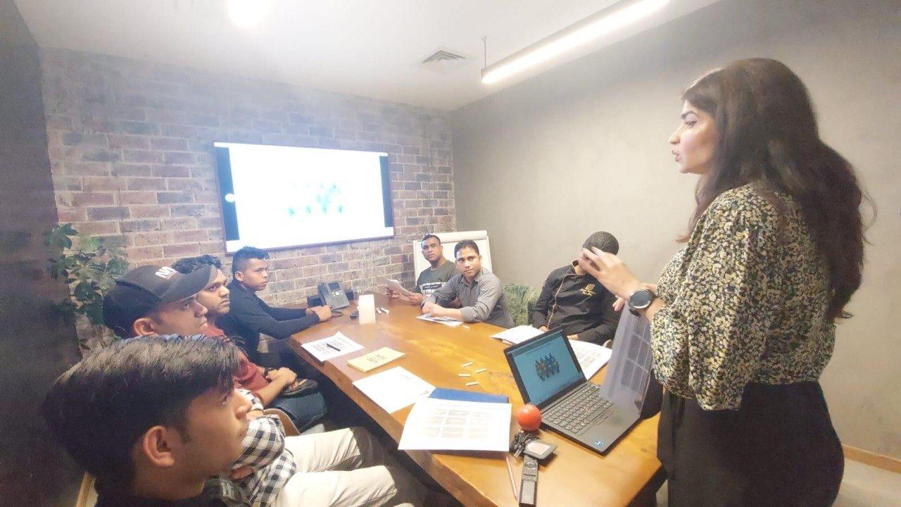Sonia Arif delivering a training session beside a screen presentation